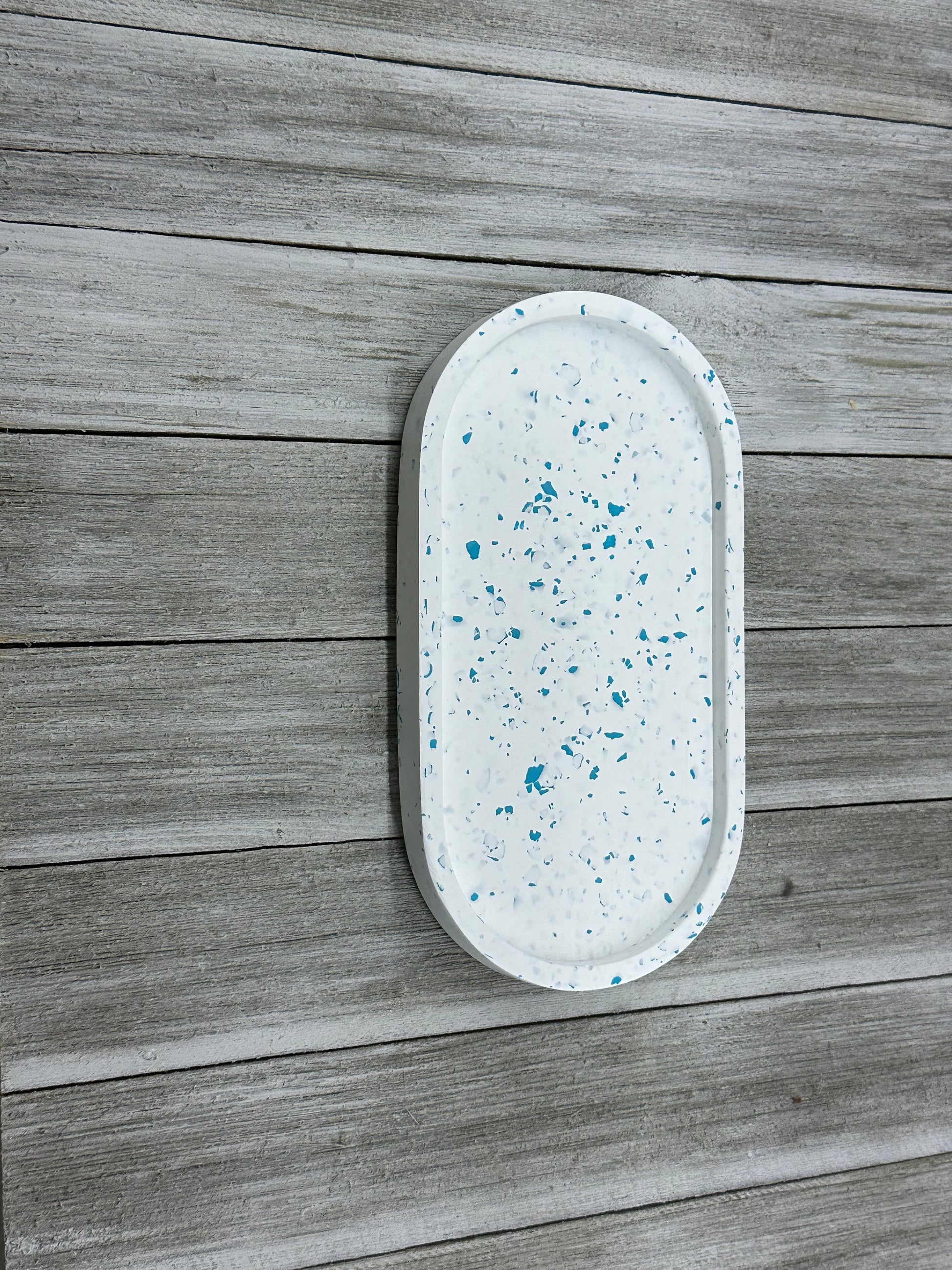 Oval-shaped tray with blue speckles on a wooden surface
