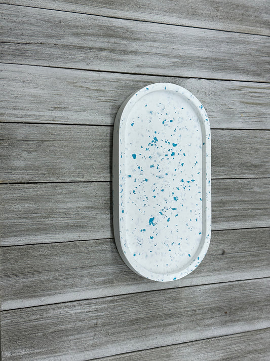 Oval-shaped tray with blue speckles on a wooden surface